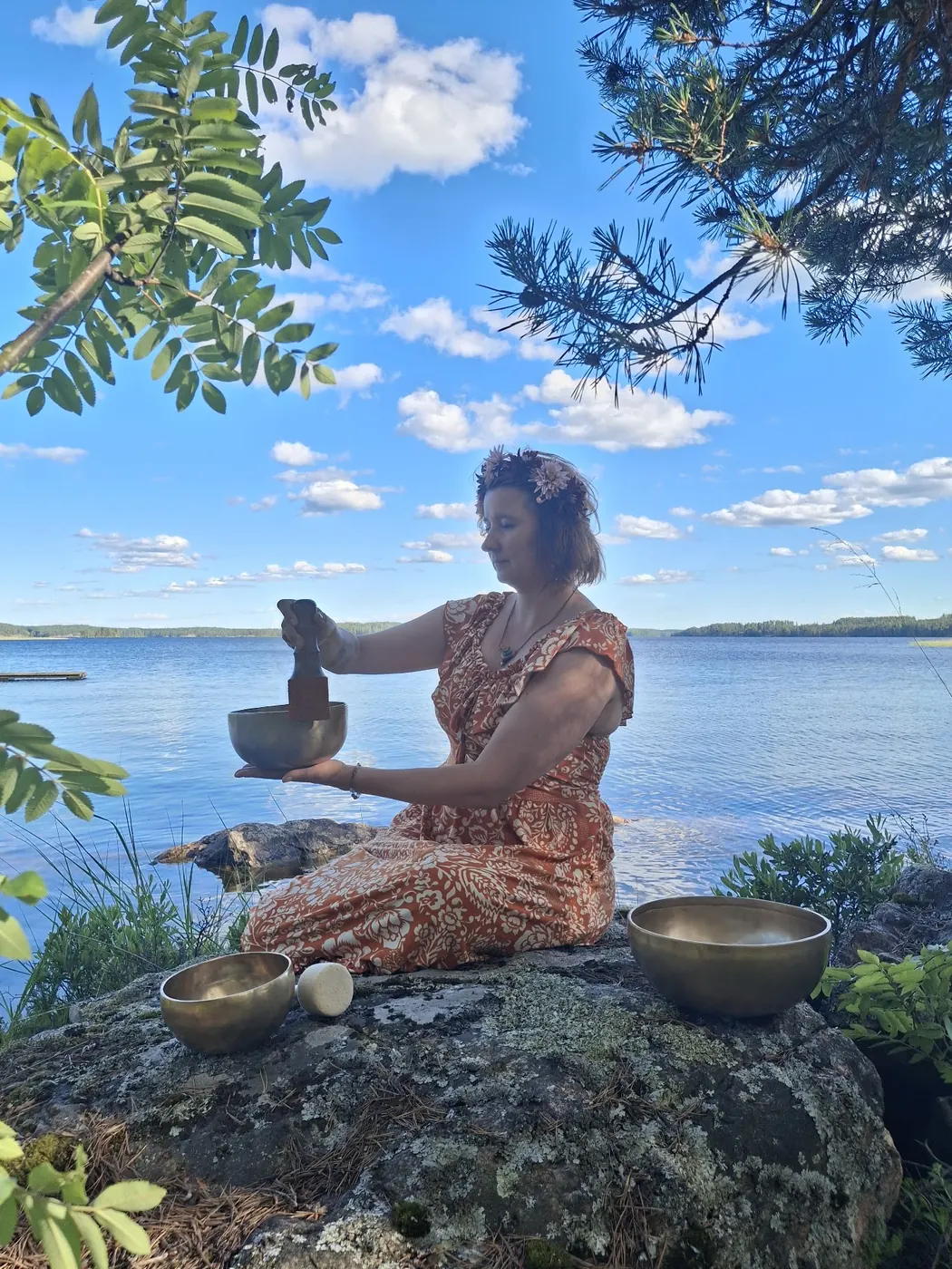 Äänimaljan soittaja kalliolla järven rannalla