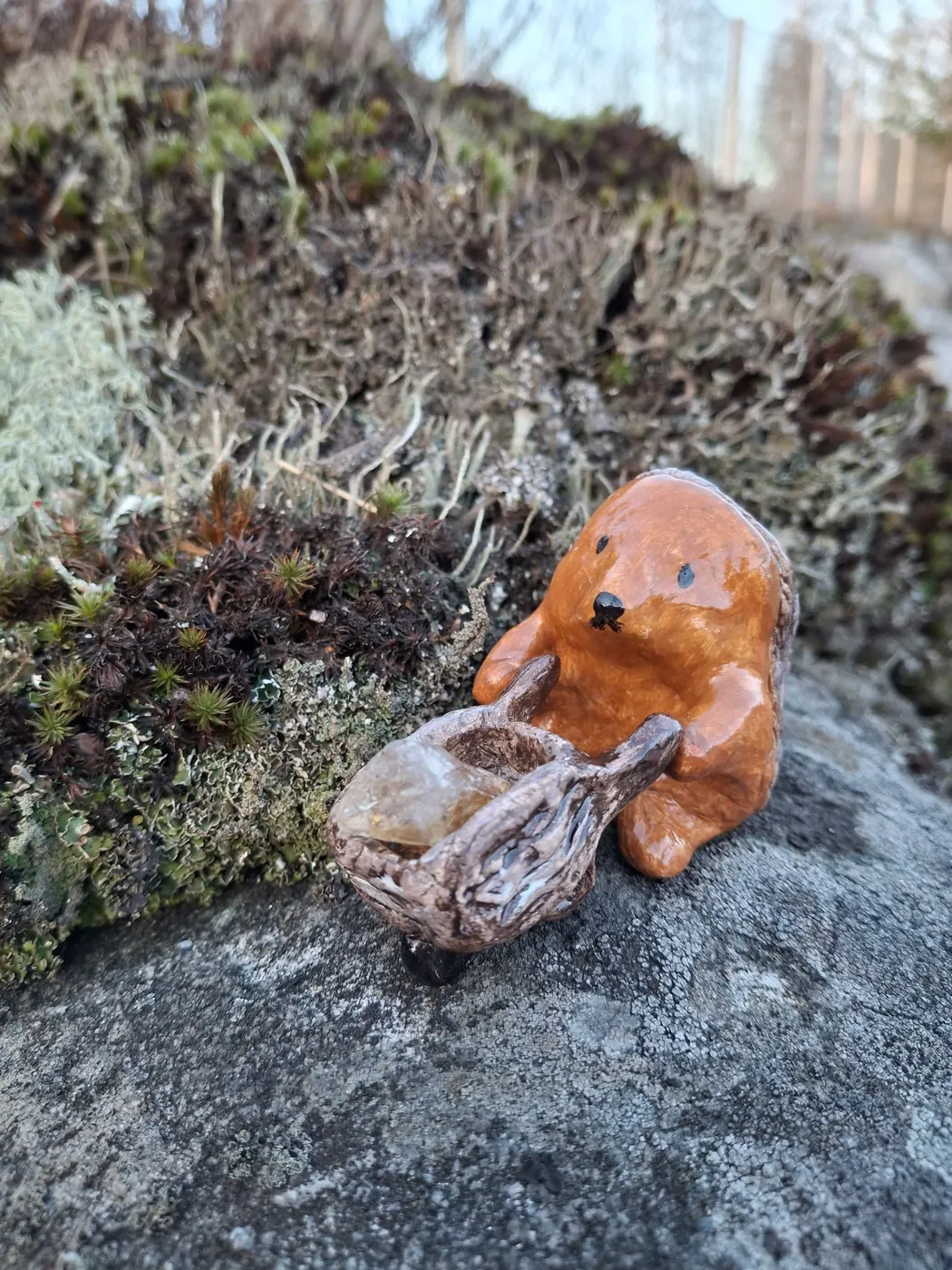 Karhu ja puinen kulho kristallin kanssa kalliolla